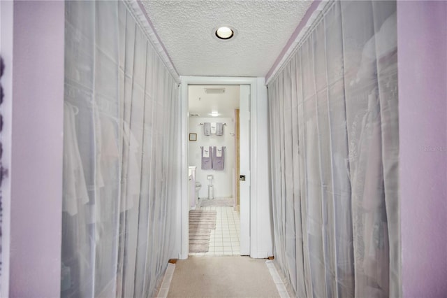 hallway featuring light tile patterned flooring and a textured ceiling