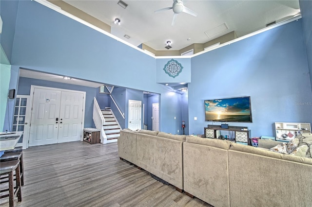 unfurnished living room with ceiling fan, wood-type flooring, and a high ceiling