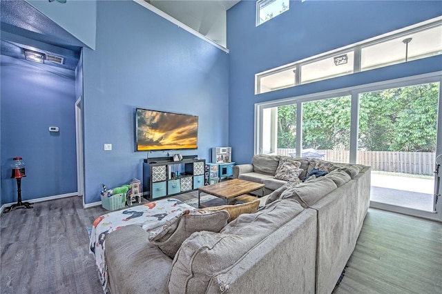 living room with wood-type flooring and a towering ceiling