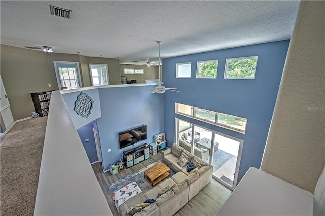 living room with ceiling fan, hardwood / wood-style floors, and a textured ceiling