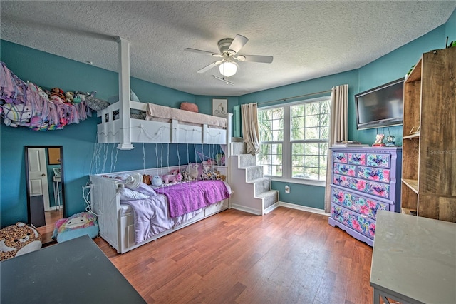 bedroom with hardwood / wood-style flooring, ceiling fan, and a textured ceiling