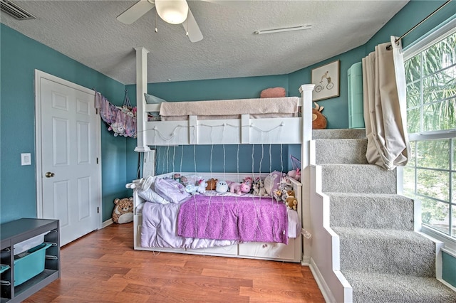 bedroom featuring hardwood / wood-style floors, a textured ceiling, and ceiling fan