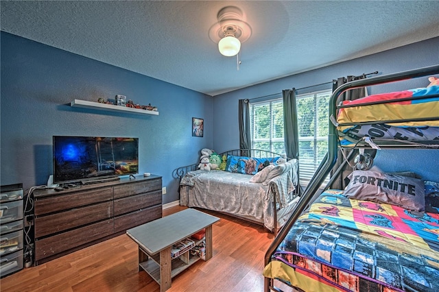 bedroom with hardwood / wood-style floors, ceiling fan, and a textured ceiling