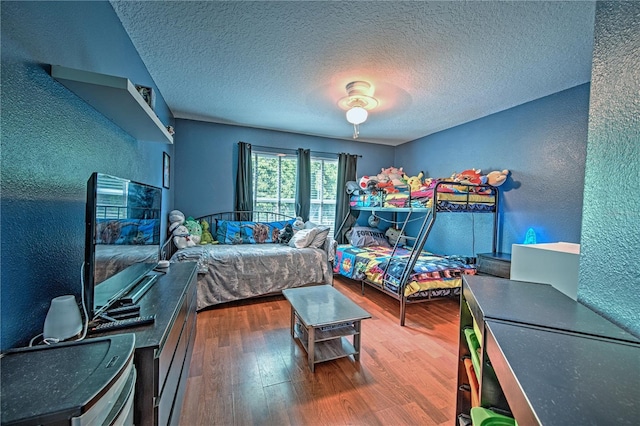 bedroom with a textured ceiling, hardwood / wood-style flooring, and ceiling fan