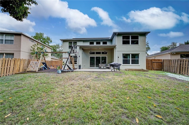 back of house with a lawn, a patio area, and a playground