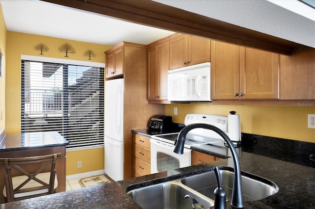 kitchen featuring dark stone countertops, a wealth of natural light, sink, and white appliances