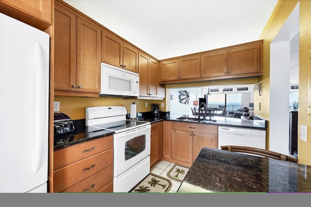 kitchen with a textured ceiling, white appliances, sink, and dark stone counters