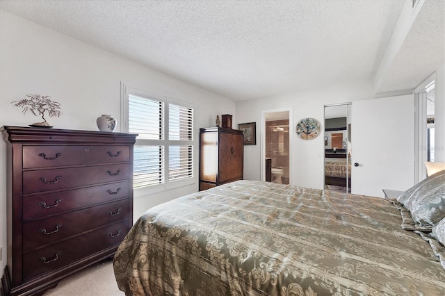 bedroom with connected bathroom, light carpet, and a textured ceiling