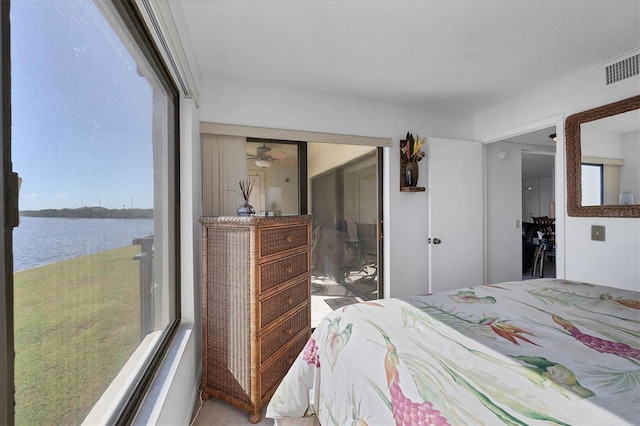 bedroom with a water view, a textured ceiling, and a closet