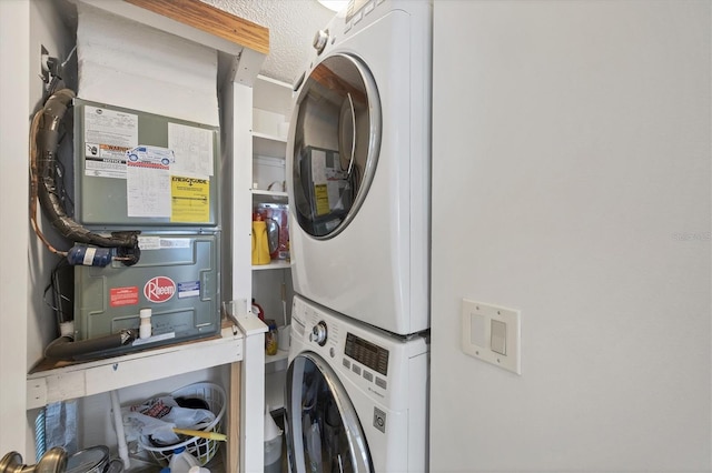 laundry area featuring a textured ceiling, heating unit, and stacked washer / drying machine