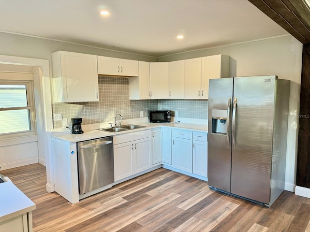 kitchen with sink, white cabinets, light wood-type flooring, and appliances with stainless steel finishes