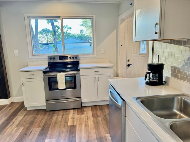 kitchen with stainless steel appliances, white cabinetry, hardwood / wood-style flooring, and sink