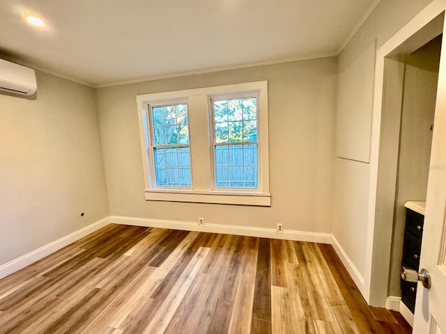 empty room with wood-type flooring, a wall unit AC, and crown molding