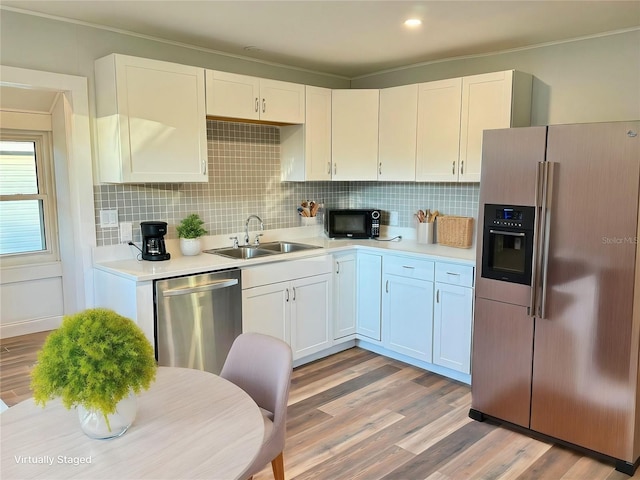 kitchen with stainless steel appliances, white cabinetry, light hardwood / wood-style floors, and sink