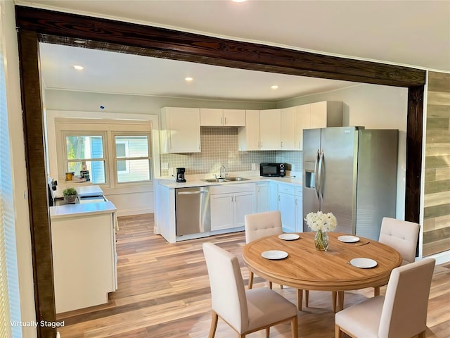 kitchen with white cabinetry, sink, light hardwood / wood-style flooring, and appliances with stainless steel finishes