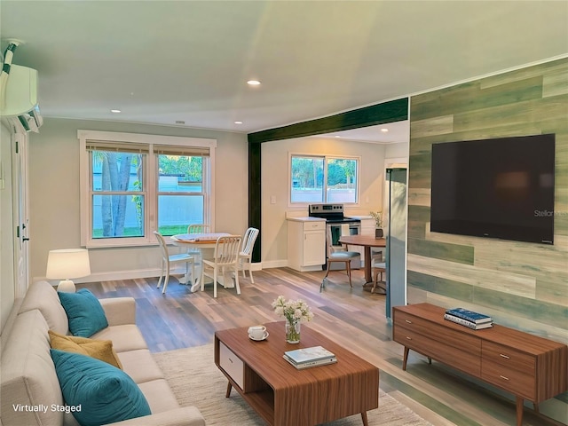 living room with a wall unit AC and light hardwood / wood-style flooring