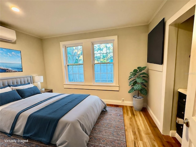 bedroom with a wall unit AC, crown molding, and light wood-type flooring