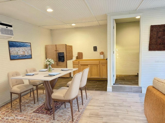 dining area featuring an AC wall unit and wooden walls