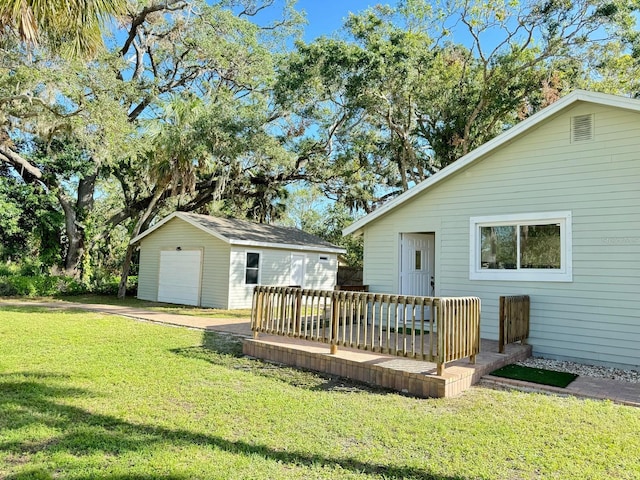 rear view of house featuring a deck, a garage, an outdoor structure, and a lawn