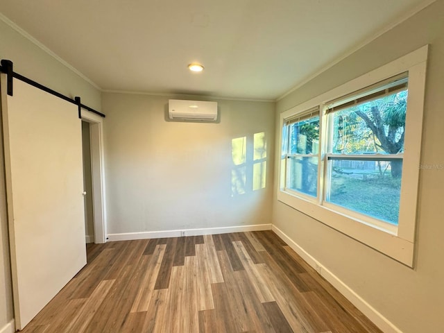 empty room with hardwood / wood-style flooring, a barn door, crown molding, and a wall mounted AC