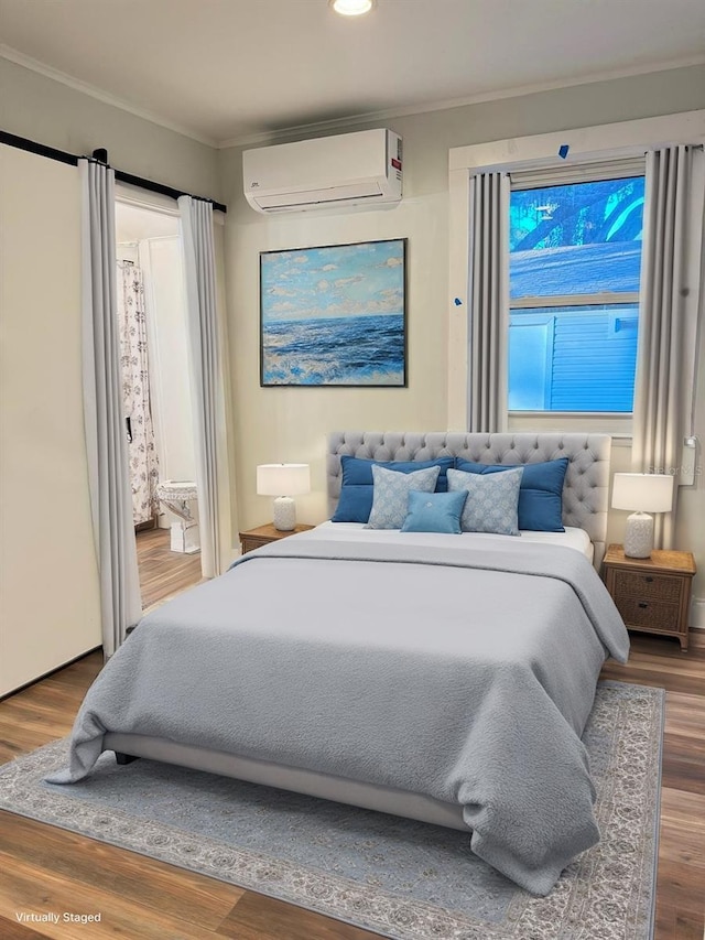 bedroom with a wall mounted air conditioner, wood-type flooring, and crown molding