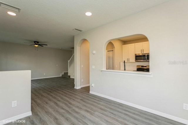 unfurnished living room featuring ceiling fan, hardwood / wood-style floors, and a textured ceiling