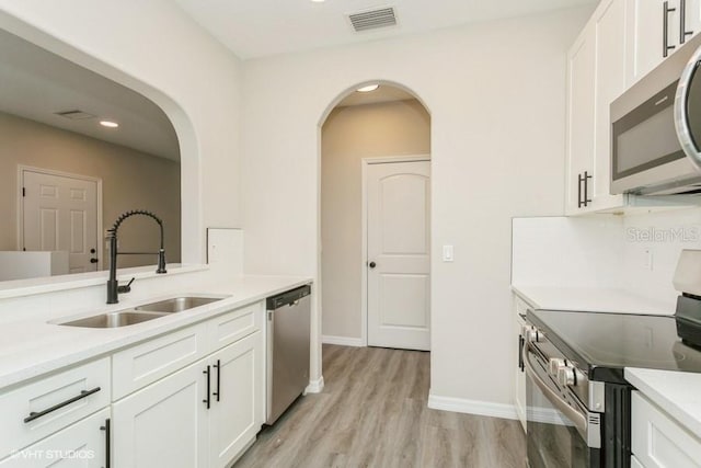 kitchen with white cabinetry, sink, stainless steel appliances, and light wood-type flooring