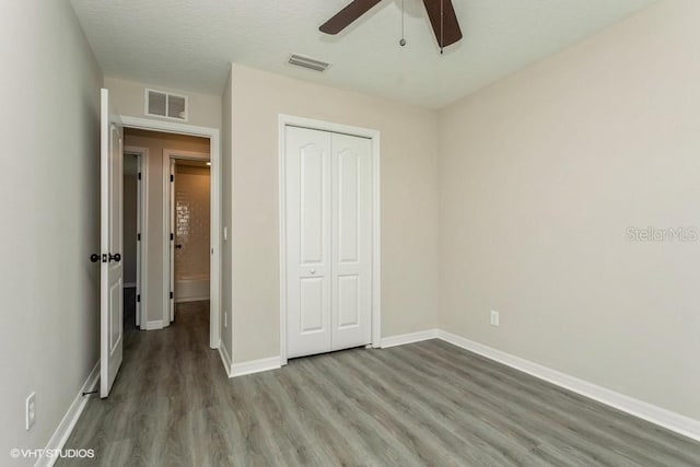 unfurnished bedroom with hardwood / wood-style floors, ceiling fan, a textured ceiling, and a closet