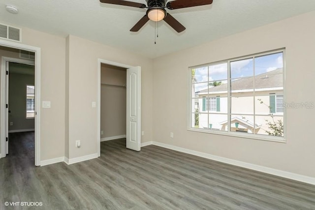 unfurnished bedroom featuring ceiling fan, a closet, dark wood-type flooring, and multiple windows