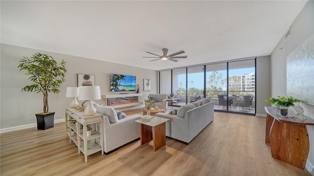 living room featuring ceiling fan, a wall of windows, and light wood-type flooring