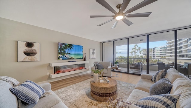 living room with wood-type flooring, floor to ceiling windows, and ceiling fan