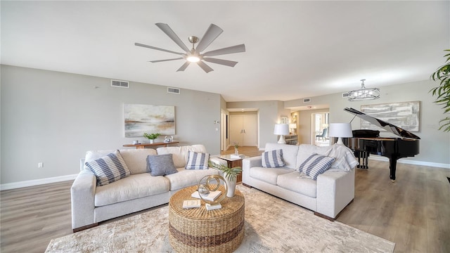 living room with ceiling fan with notable chandelier and light hardwood / wood-style floors