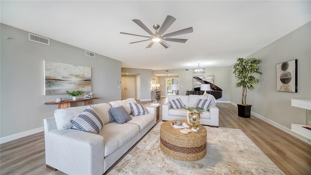 living room featuring light hardwood / wood-style floors and ceiling fan with notable chandelier