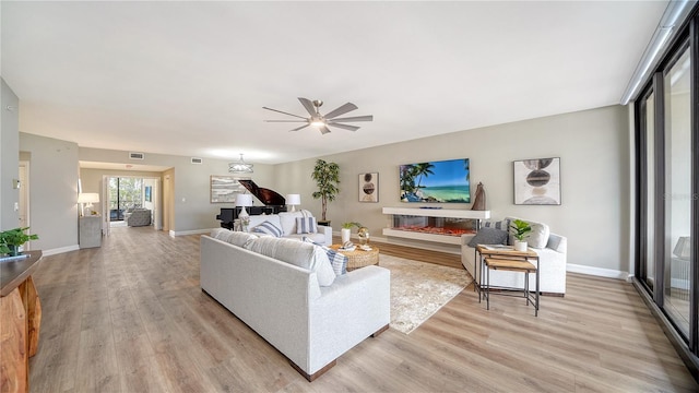 living room with ceiling fan, a fireplace, and light wood-type flooring