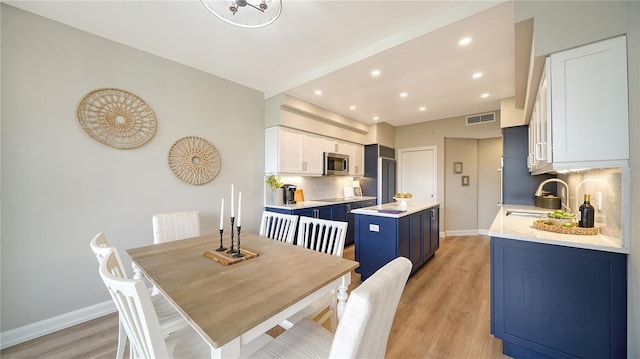 dining room with vaulted ceiling, sink, and light hardwood / wood-style flooring