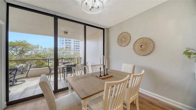 dining room with a notable chandelier, expansive windows, and light wood-type flooring