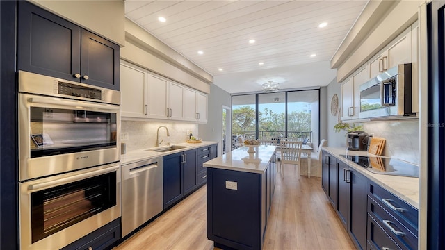 kitchen with a center island, sink, decorative backsplash, white cabinets, and appliances with stainless steel finishes