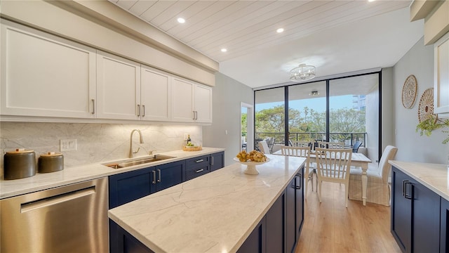 kitchen with light stone countertops, sink, blue cabinetry, dishwasher, and white cabinets