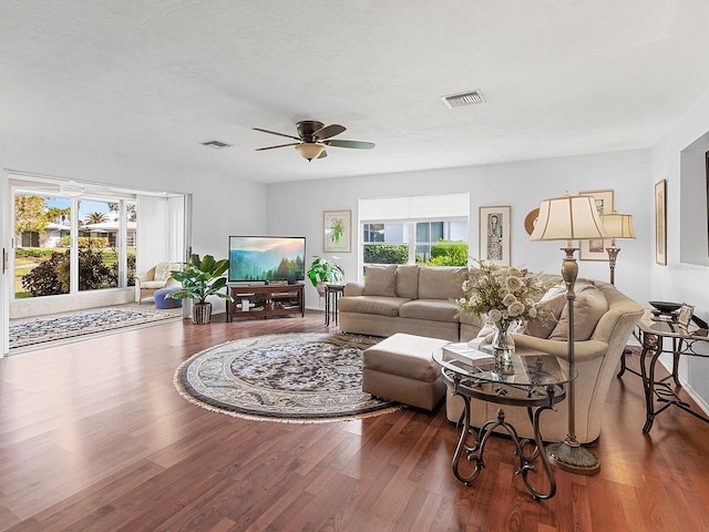 living room with ceiling fan, a healthy amount of sunlight, wood-type flooring, and a textured ceiling