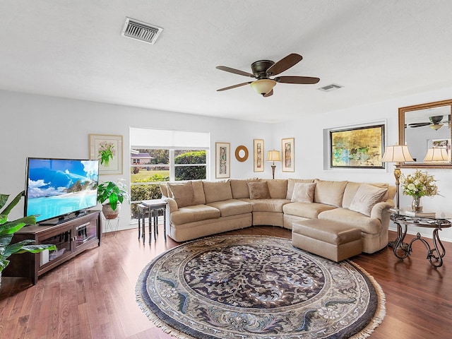 living room with ceiling fan, dark wood-type flooring, and a textured ceiling