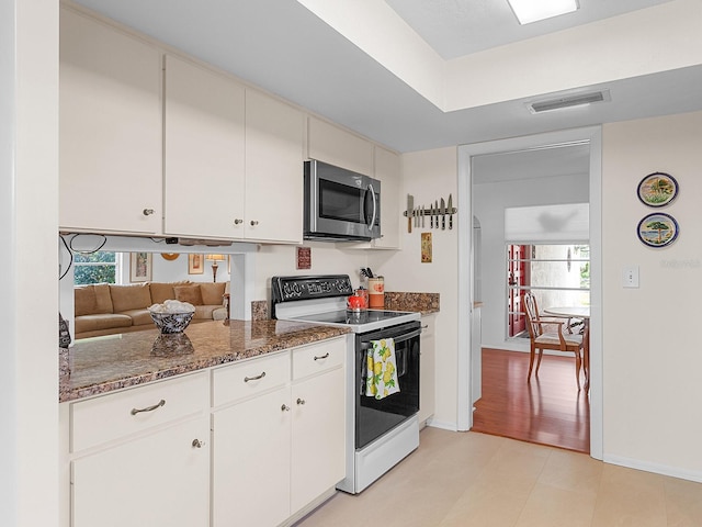 kitchen featuring white cabinets, light wood-type flooring, white electric stove, and dark stone counters