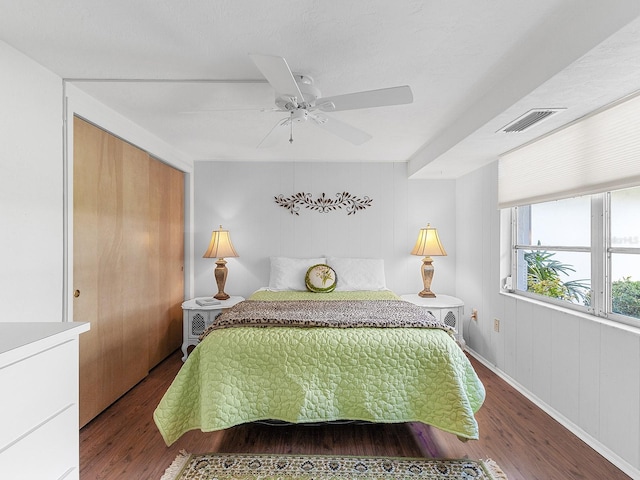 bedroom featuring hardwood / wood-style flooring, ceiling fan, and wood walls