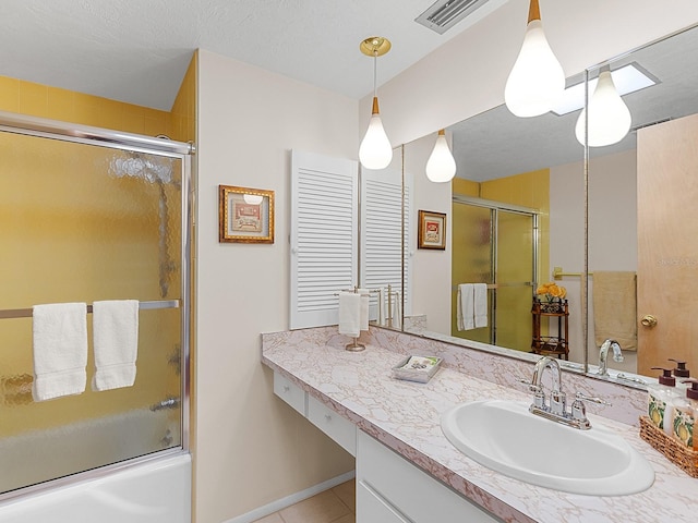 bathroom featuring tile patterned flooring, vanity, and combined bath / shower with glass door