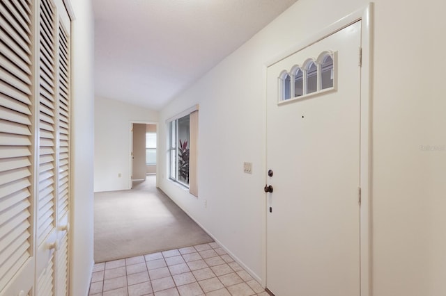 hall featuring lofted ceiling and light carpet