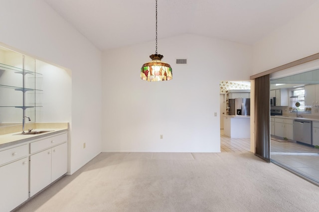 unfurnished dining area with sink, light colored carpet, and vaulted ceiling