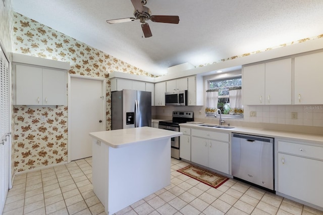 kitchen featuring stainless steel appliances, ceiling fan, sink, light tile patterned floors, and white cabinetry