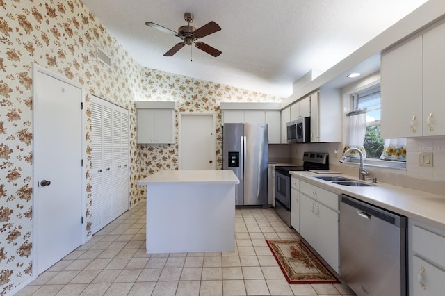 kitchen featuring lofted ceiling, white cabinets, sink, appliances with stainless steel finishes, and light tile patterned flooring