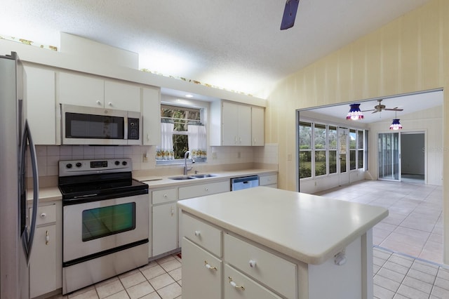 kitchen featuring appliances with stainless steel finishes, white cabinetry, a kitchen island, and sink