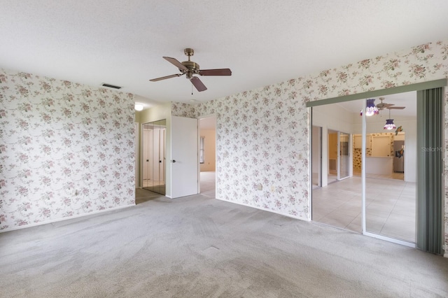 carpeted spare room featuring a textured ceiling and ceiling fan