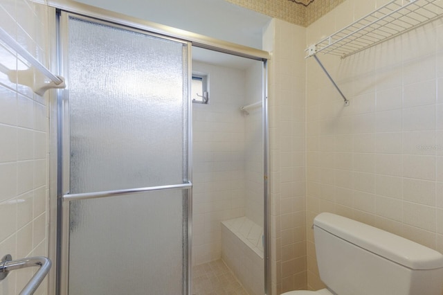 bathroom with a shower with door and toilet